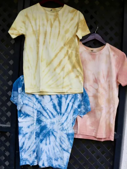 Three of our naturally dyed tees, showcasing different colors and tie-dye patterns. These are perfect for anyone who loves unique, sustainable clothing.