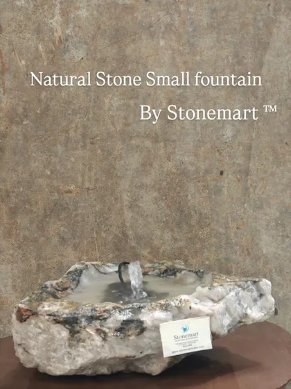 A small fountain carved from natural stone, perfect for adding a touch of rustic charm to any space.