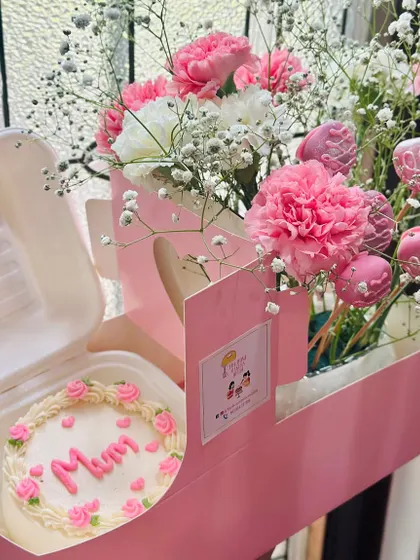 Another angle of our popular Mother's Day hamper. This view highlights the 'Mum' bento cake and the bouquet of pink carnations and glittery cake pops.