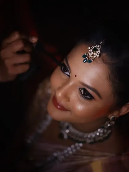A close up of the final touches. I am applying mascara to define the eyes, creating a glossy, dramatic look that stands out beautifully in photos and under the evening lights for a reception.