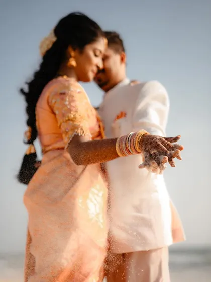 An intimate close-up of a couple on the beach, with sand slipping through their fingers. This artistic shot focuses on the small, sensory details that make a destination wedding so special.