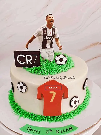A cake for a Ronaldo fan, featuring a CR7 figure, his jersey number, and a buttercream grass field.