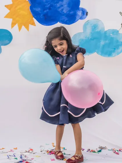 Classic elegance in a deep navy blue. This dress features a beautifully structured skirt with delicate pink piping for a subtle contrast, perfect for a sophisticated yet playful party look.