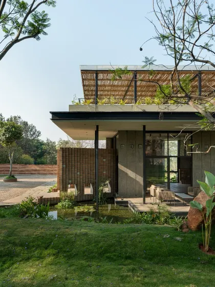 This perspective shows how the structure opens up to the landscape, with a small pond and native plantings at its edge. The design encourages a direct connection with nature, making the garden an extension of the building itself.