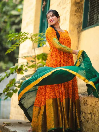 The 'Naaranghi' series, featuring a vibrant orange Anarkali-style gown with a green dupatta. The flowing fabric and bright colors create a joyful and energetic look.