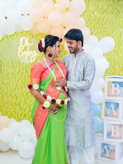A lovely portrait of the expecting couple at their baby shower. The "Oh Baby" neon sign and pastel balloon decor create a modern and sweet setting for their celebration.