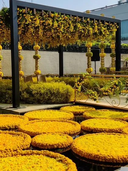 Floating discs of yellow marigolds in the water body at the residence, tying the entire space into the sunshine theme. The golden pillars in the background add a touch of traditional elegance.