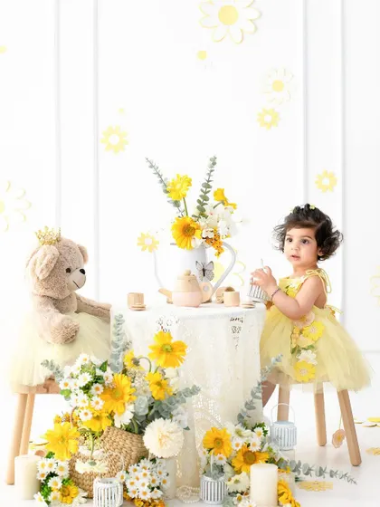 A whimsical teddy bear tea party for a sweet toddler. The vibrant yellow floral theme creates a cheerful, sunny atmosphere, perfect for capturing her innocent joy and imagination.