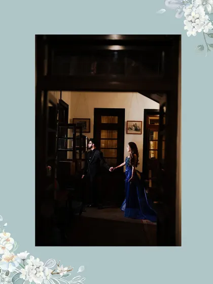An atmospheric shot of the couple, framed by a doorway. The low light and their hand-in-hand pose create a sense of intimacy and romance.