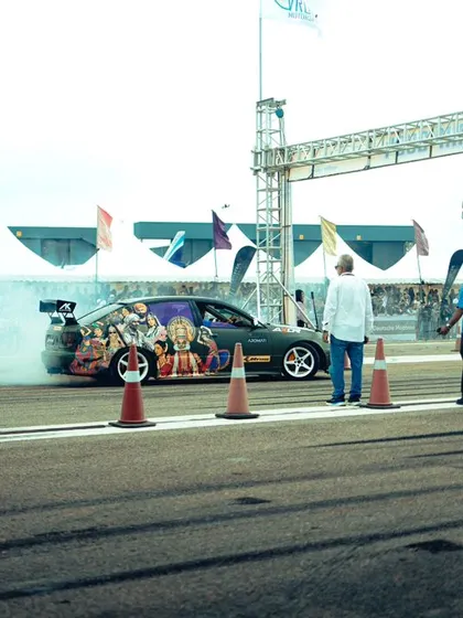 A custom-wrapped car prepares for launch, smoke billowing from the tires. This is the pre-race ritual, a spectacle of power and intimidation right at the starting line.