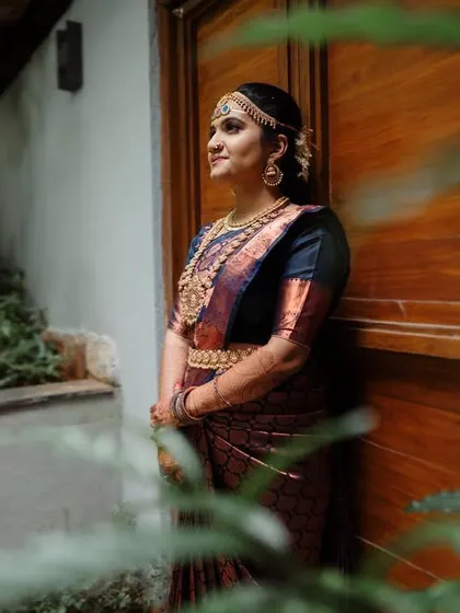 A bride standing in a beautiful courtyard, framed by lush greenery. The natural setting and soft light create a serene and timeless portrait.