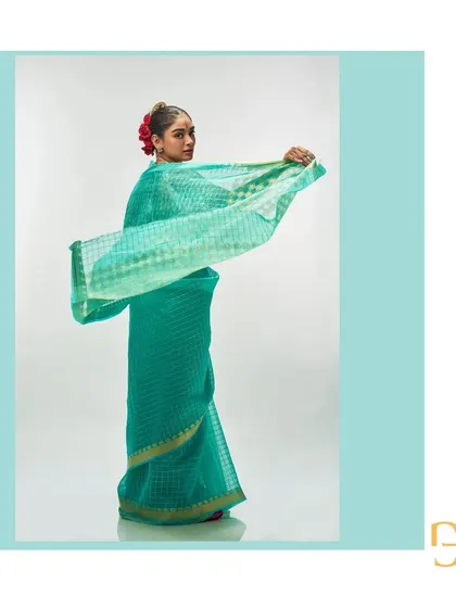 The light sea green saree captured in motion, emphasizing its airy quality and the shimmering gold checks.
