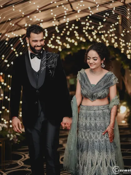 A happy couple walking hand-in-hand under a tunnel of fairy lights at their Jim Corbett engagement. This photo captures the joy and magical ambiance of a destination event.
