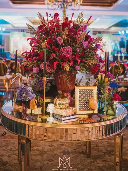 A grand centerpiece on a mirrored table, featuring a large, lush floral arrangement, candles, and various decorative objects to create a rich, layered look.
