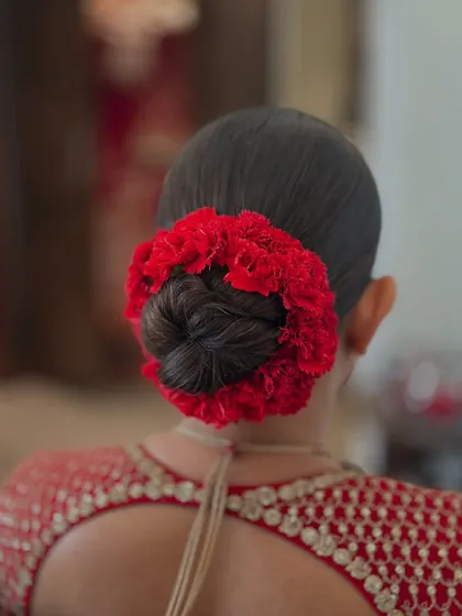 Another angle of the classic bridal bun with a red floral gajra, showing its fullness and perfect shape.