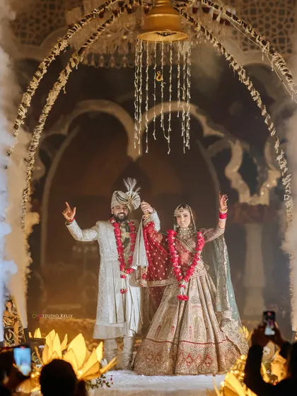 A grand entry for the couple, with smoke effects and a beautiful floral arch, setting a magical tone for the wedding.
