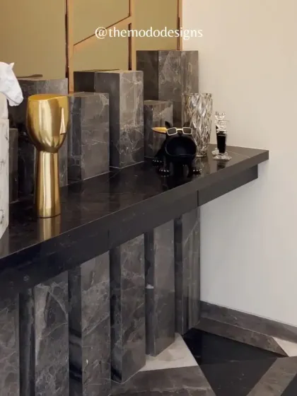 This custom console table is a work of art, crafted from geometric blocks of grey marble. It serves as a stunning platform for curated decor, making a bold statement in the entryway.