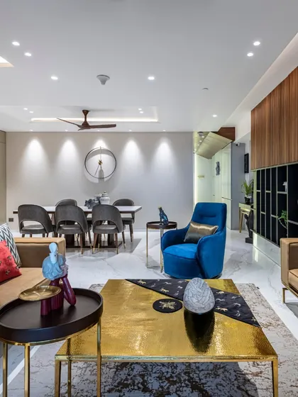 A complete view of the Filigree House living and dining area. The space is unified by a consistent palette of neutral tones, rich woods, and a striking pop of royal blue, creating a cohesive and sophisticated open-plan environment.