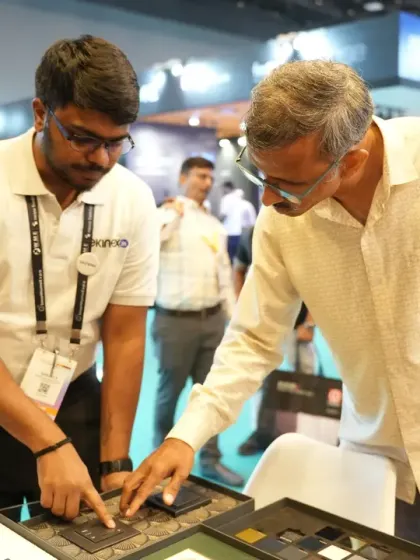 An exhibitor demonstrates the fine details of a smart switch panel to an interested architect. These interactions are key for showcasing product design and functionality to decision-makers.