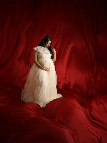 A pensive and beautiful portrait, with the soft cream gown standing out against the deep red fabric.