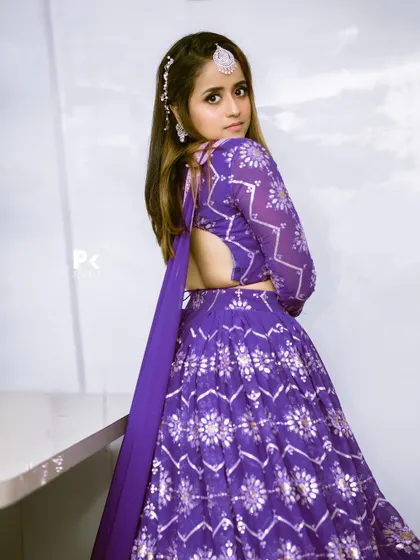The back view of a vibrant purple lehenga with silver foil print, showing off its backless blouse design.