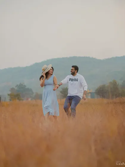 A fun and energetic shot of the couple running and laughing through a field of golden grass.