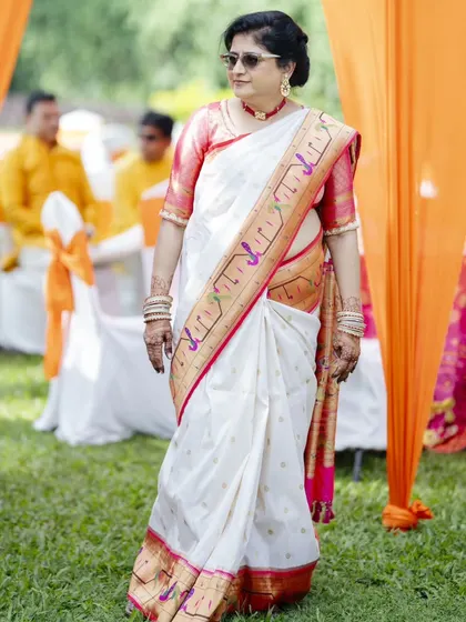 The mother of the bride looking chic and stylish at the outdoor haldi ceremony. Her hair is neatly styled, and the makeup is fresh and appropriate for the daytime.