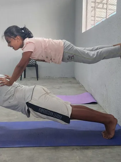 A different angle of the wall-assisted partner plank, showing the alignment and muscle engagement required.