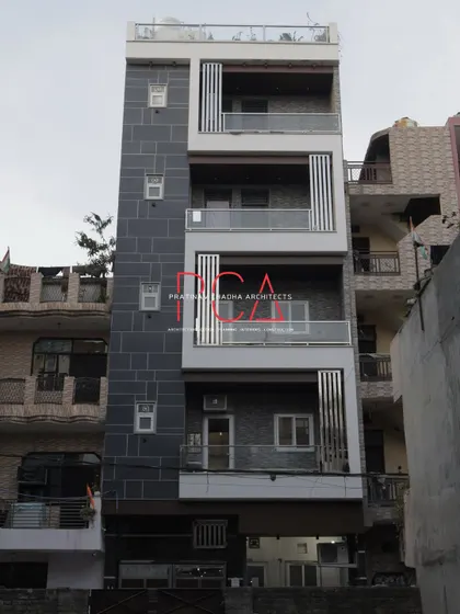 The Cursive Abode facade during the day, showing the material palette of dark stone tiles and white accents. The design provides a clean, contemporary look that stands out.