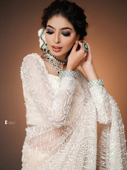The soft curls and white flower in the hair add a romantic touch to this modern look.