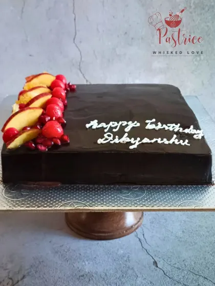 A sleek Dutch truffle sheet cake, elegantly garnished with fresh peaches and pomegranate seeds.