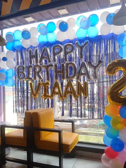 A simple yet effective birthday decoration on a large window. This setup with a balloon garland and foil letters is great for cafes or restaurants.