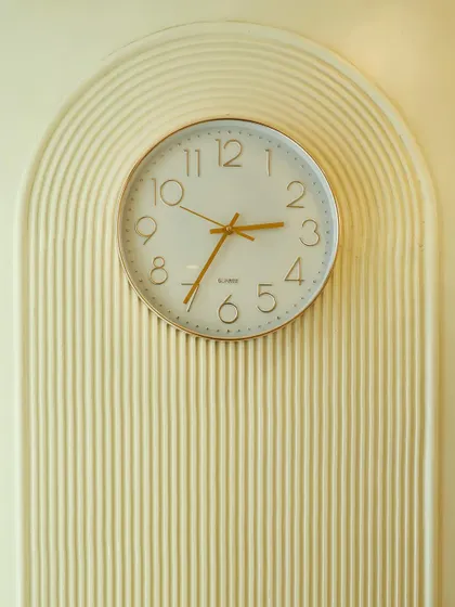 A close-up of the wall clock set within a fluted arch, a small detail that reinforces the room's cohesive design theme.