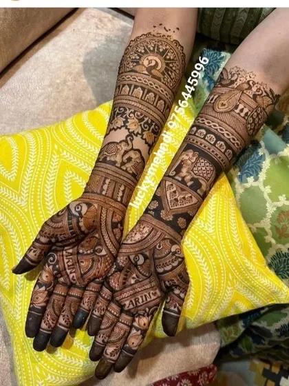 This design features names hidden within the intricate patterns on the palms. The arms are decorated with traditional elephant and peacock motifs.