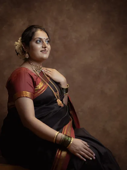 This classic seated portrait captures a moment of quiet reflection. The traditional silk saree and jewelry add a layer of cultural richness to this elegant maternity photograph.