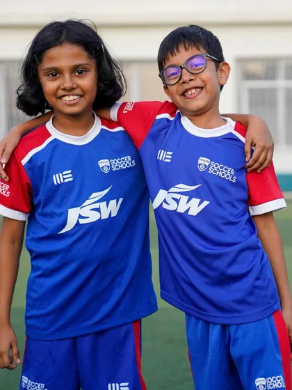 Friends for life, united through football. Two young players share a happy moment on the pitch.