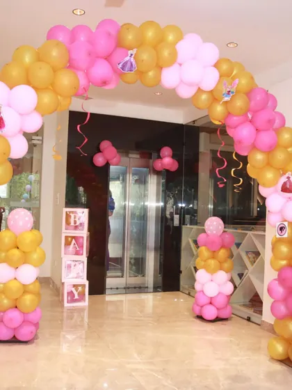 The indoor entrance to a Barbie party, with a pink and gold balloon arch leading the way. Even the elevator area is part of the celebration!