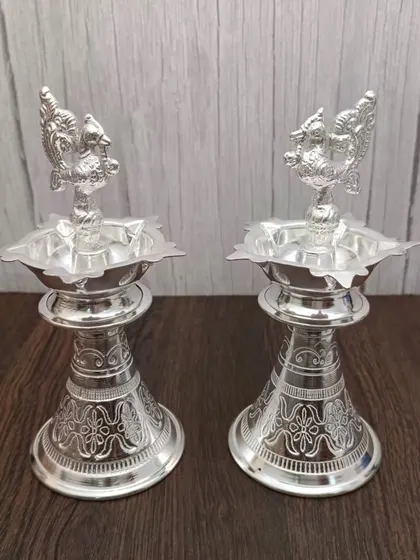 Another view of the German silver Nakashi deepa pair, highlighting the floral carving details. These lamps are crafted to look beautiful from every angle.