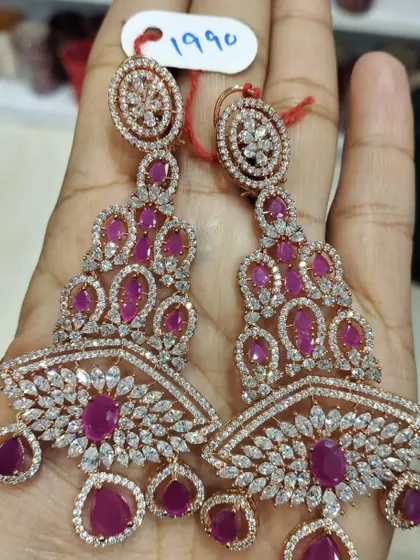 A pair of heavy, chandelier-style earrings in rose gold polish with ruby-coloured stones. These are designed to make a statement and are perfect for a glamorous evening look.