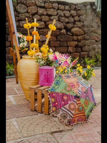 Small, colorful decor corners add to the carnival-like atmosphere. This arrangement features a traditional Rajasthani umbrella, marigolds, and other vibrant props.