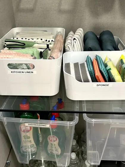 Under-sink storage can be functional too. Here, we've used labeled bins to organize kitchen linen, sponges, and dishwashing supplies, turning a typically chaotic space into an orderly one.