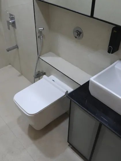 A modern washroom with a wall-mounted toilet and a sleek vanity. The combination of light and dark tiles adds contrast.