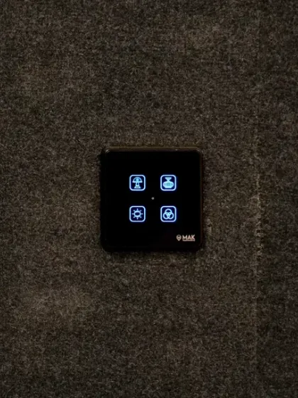 A small, four-button smart panel installed in a matte black themed home theater, providing discreet but powerful control.