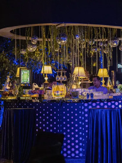A whimsical polka-dot bar setup for a Diwali party, decorated with hanging disco balls, table lamps, and bead curtains for a fun and eclectic vibe.