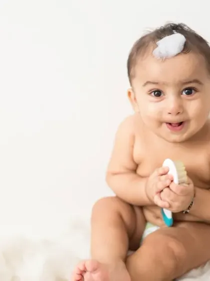 A sweet portrait of a baby sitter with a bit of foam on his head. The direct eye contact and charming smile make this an engaging and heartwarming photo for any baby-focused campaign.