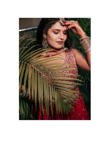 A creative portrait of the bride with a palm leaf, adding a tropical and fashionable touch.