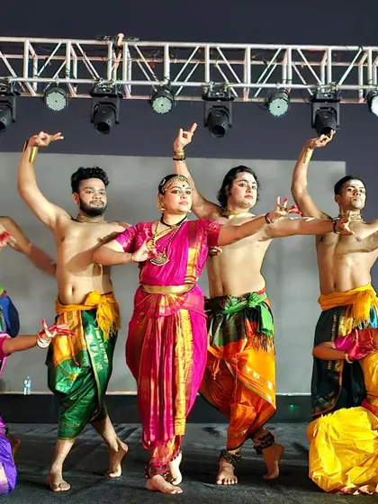 A group photo of the 'Maheswara' cast, highlighting the mix of male Chhau dancers and female Bharatanatyam dancers in colorful costumes.