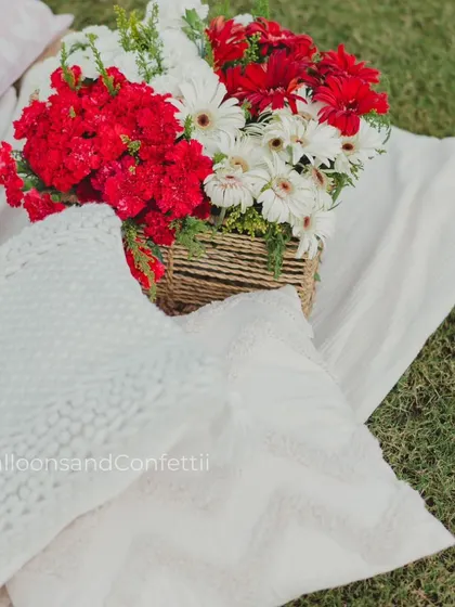 A pop of color with this beautiful floral arrangement in a rustic basket, placed on a cozy white blanket. Fresh flowers are essential to bringing any outdoor setup to life.