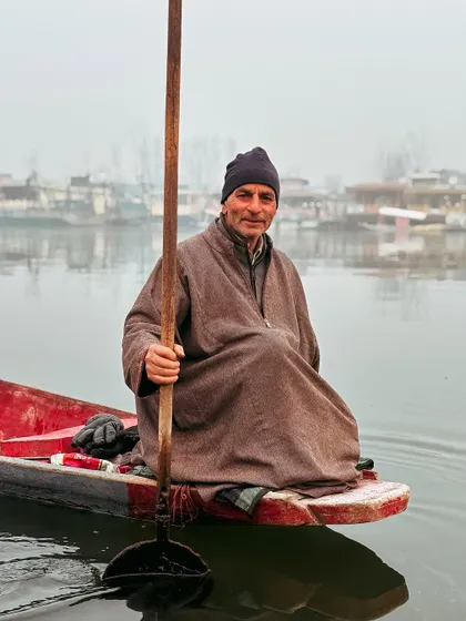 A portrait of a smiling boatman, his warmth contrasting with the cool, misty morning on the lake.