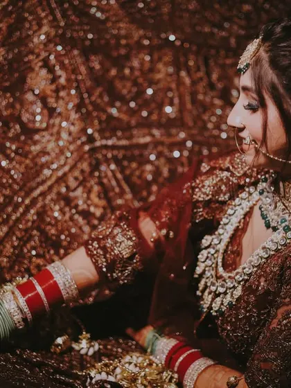 A close-up of the bride against the sparkling backdrop of her own lehenga, a creative and detailed shot.